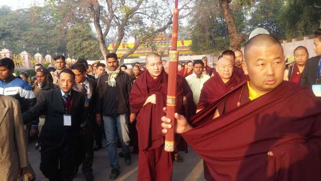 Karmapa se rend au temple Mahabodhi précédé par un porteur d'encens et suivi par la foule.